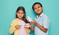 Two kids demonstrating how to brush teeth