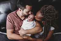 New parents kissing baby