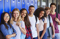Teenage schoolkids smiling to camera in school corridor