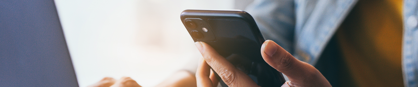 image of a person using their smartphone and laptop
